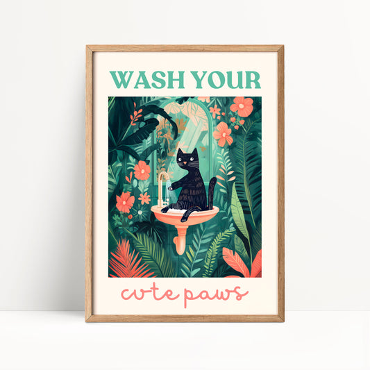The image is a framed poster with a black cat sitting in a sink surrounded by tropical plants and flowers. The poster has a green border and a pink frame. The text at the top of the poster says "WASH YOUR" and the text at the bottom says "cute paws".