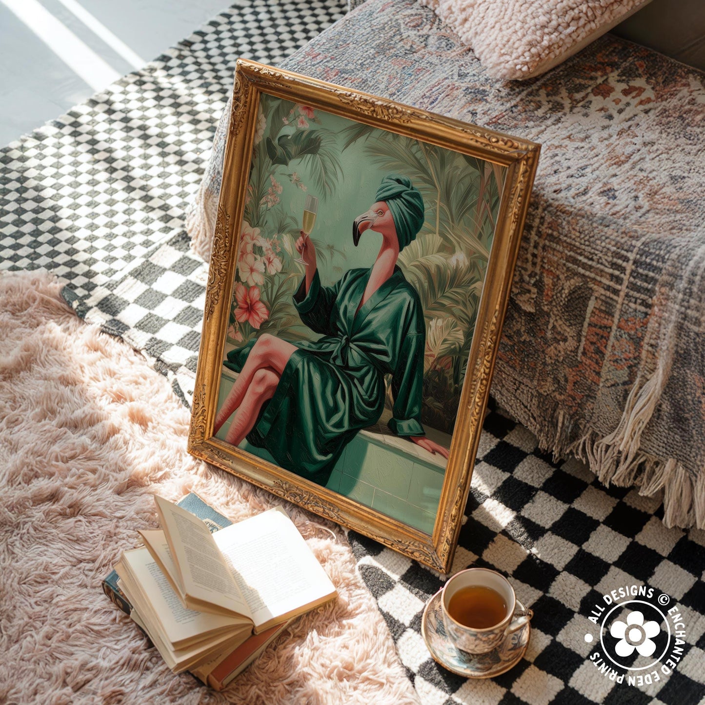 a framed painting of a woman in a green robe sitting on a bench, holding a drink, with a pink flamingo in her hand. The painting is placed on a checkered rug, and there are several books and a cup of tea nearby.