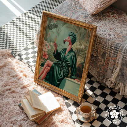 a framed painting of a woman in a green robe sitting on a bench, holding a drink, with a pink flamingo in her hand. The painting is placed on a checkered rug, and there are several books and a cup of tea nearby.
