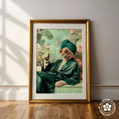 A framed print depicting a leopard wearing a green robe and holding a glass of wine, with a tropical background.