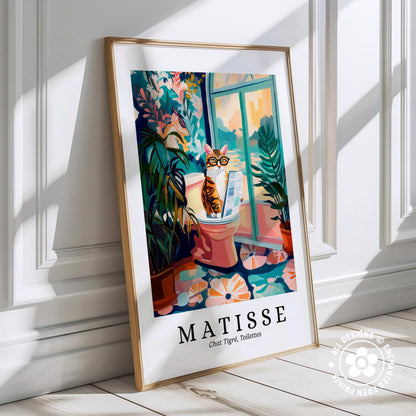 A framed poster depicting a cat sitting on a toilet in a colorful, whimsical setting with plants and flowers.