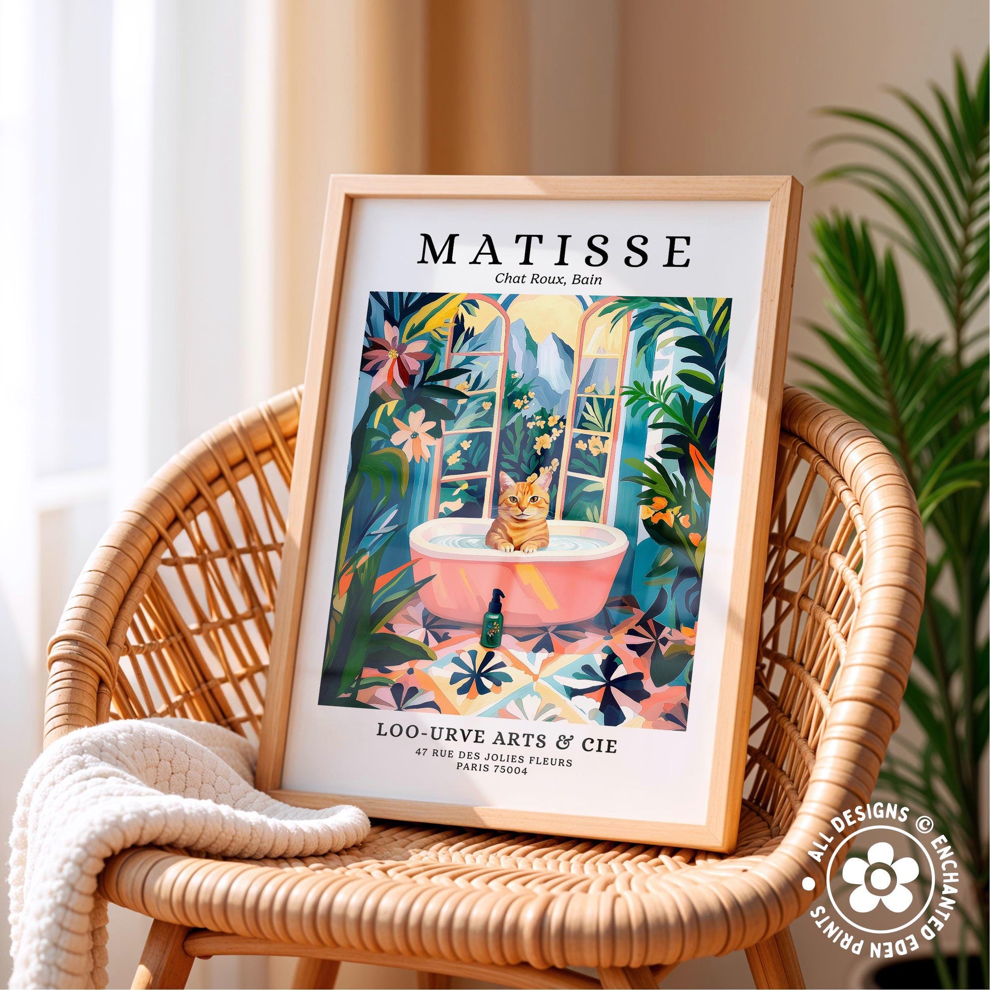 A framed poster of a cat sitting in a bathtub, surrounded by tropical plants, is displayed on a wicker chair.