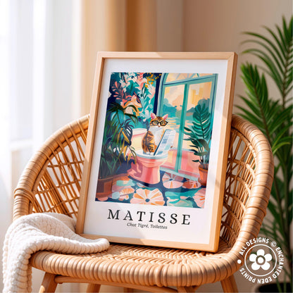A framed poster of a cat sitting on a toilet in a colorful, whimsical illustration is displayed on a wicker chair.