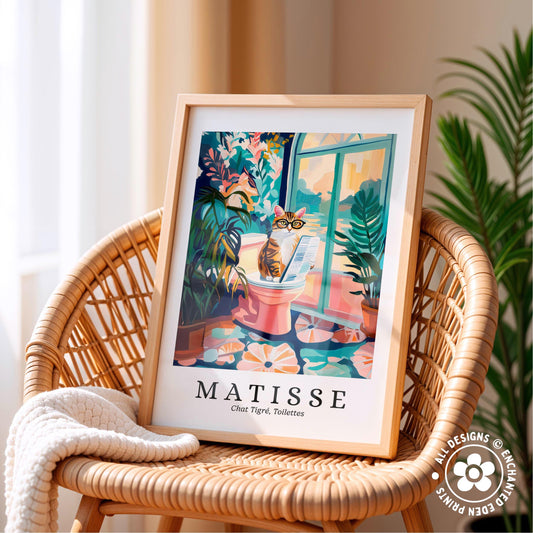A framed poster of a cat sitting on a toilet in a colorful, whimsical illustration is displayed on a wicker chair.