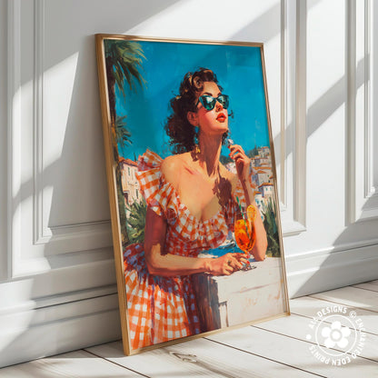 A framed painting depicting a woman in a red and white checkered dress, wearing sunglasses and holding a drink, standing on a balcony overlooking a cityscape.