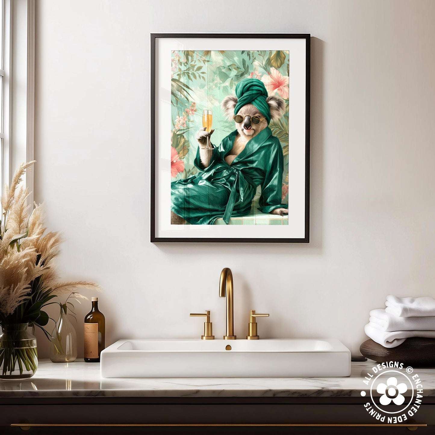 a framed picture of a koala wearing a green robe and holding a glass of champagne, sitting on a white marble countertop in a bathroom setting.