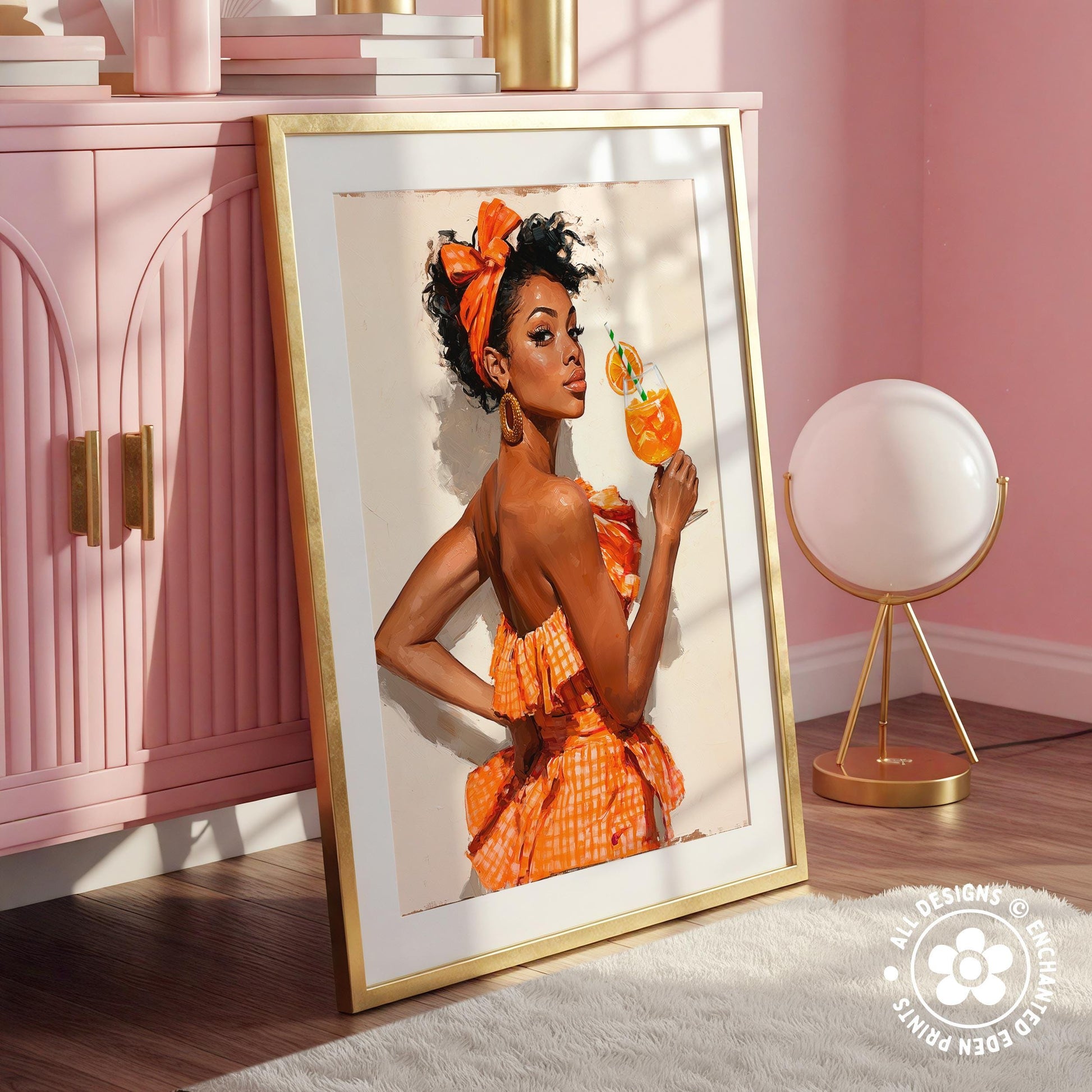 A framed photograph of a woman in an orange dress holding a drink, standing in a pink room with a lamp and a pink cabinet in the background.