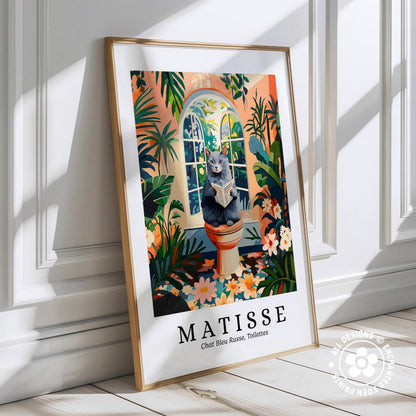 A framed poster of a cat sitting on a pedestal in a tropical garden, surrounded by colorful flowers and plants.