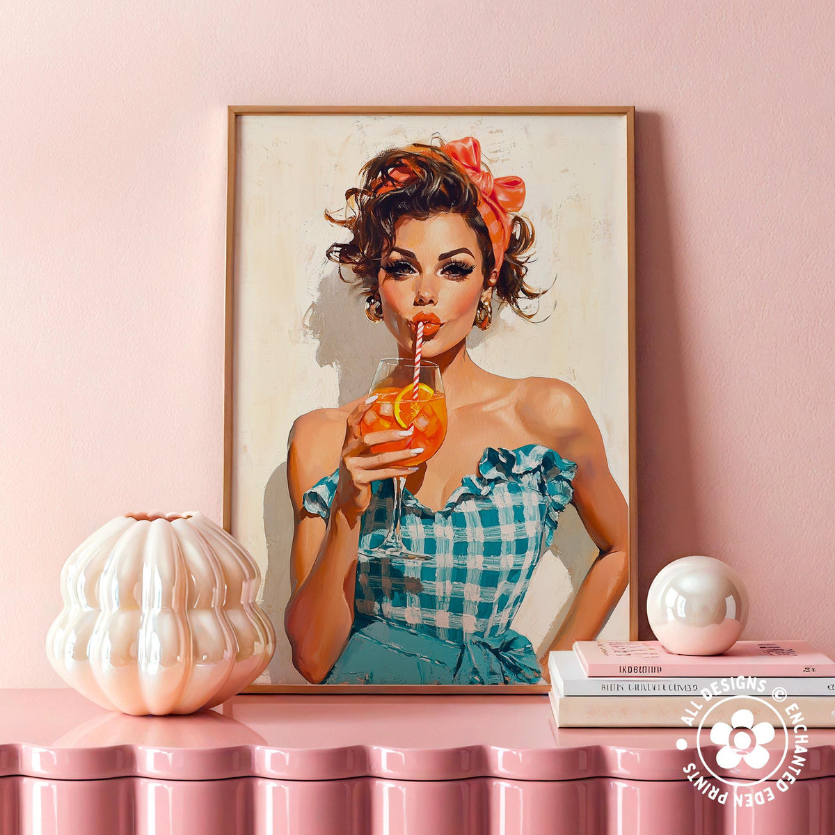 a framed painting of a woman in a blue and white checkered dress, holding a drink and wearing a red headband. The painting is displayed on a pink shelf, with a white vase and a stack of books placed next to it.
