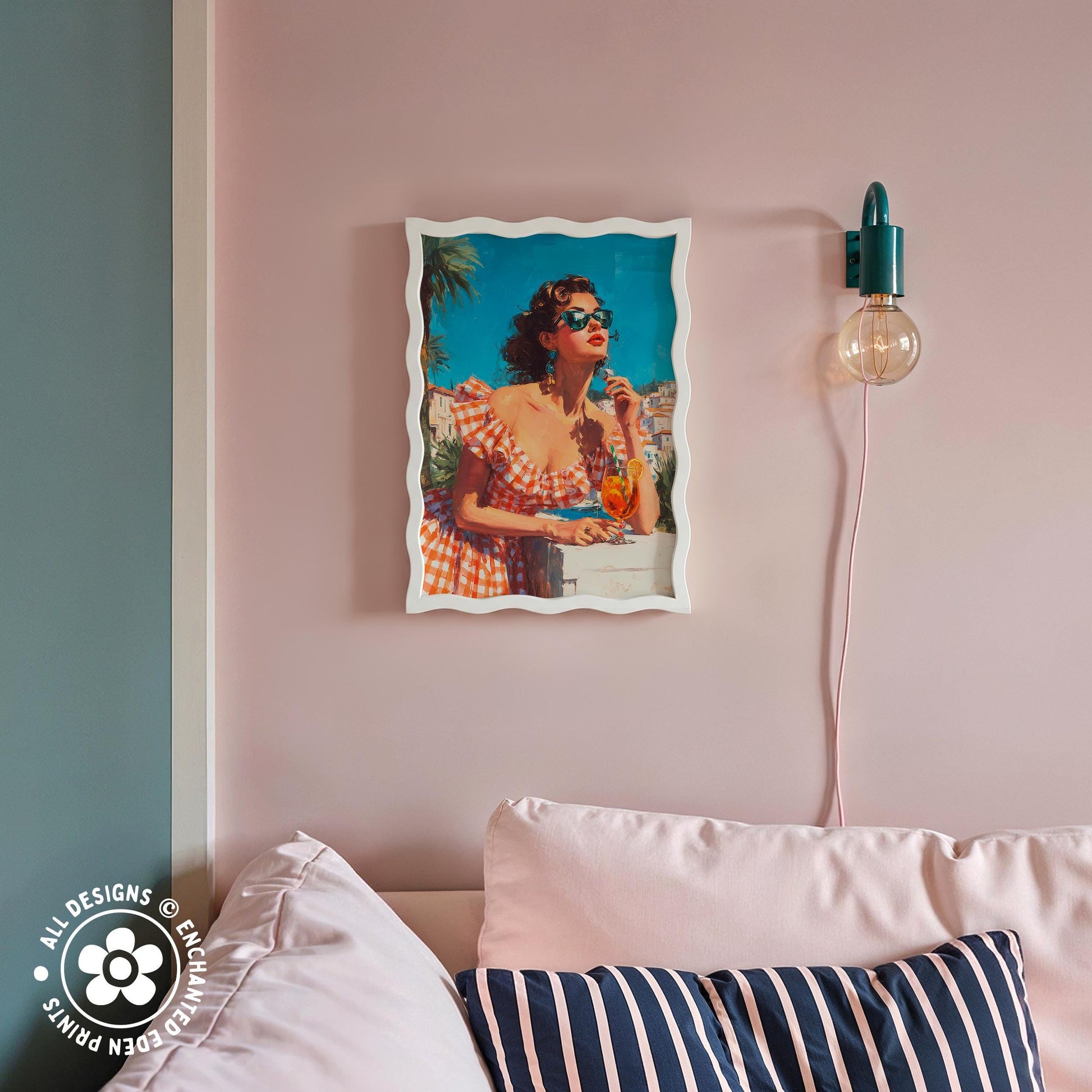 a framed vintage-style photograph of a woman in a red and white dress, sitting on a couch and holding a drink. The photograph is hanging on a pink wall above a striped pillow.