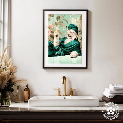 a framed picture of a cat wearing a green robe and holding a glass of wine, sitting on a white marble countertop in a bathroom setting.