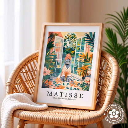 A framed illustration of a cat sitting on a windowsill, surrounded by tropical foliage, is displayed on a wicker chair.