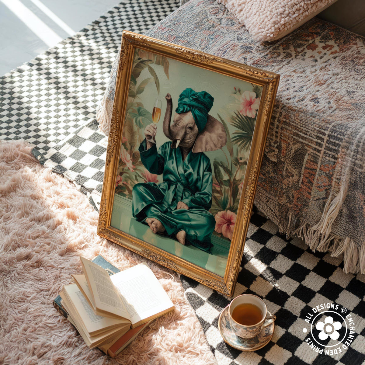 a framed painting of an elephant dressed in a green robe and turban, sitting on a bed and holding a cup of tea. The painting is placed on a pink shag rug, and there are several books and a cup of tea nearby.