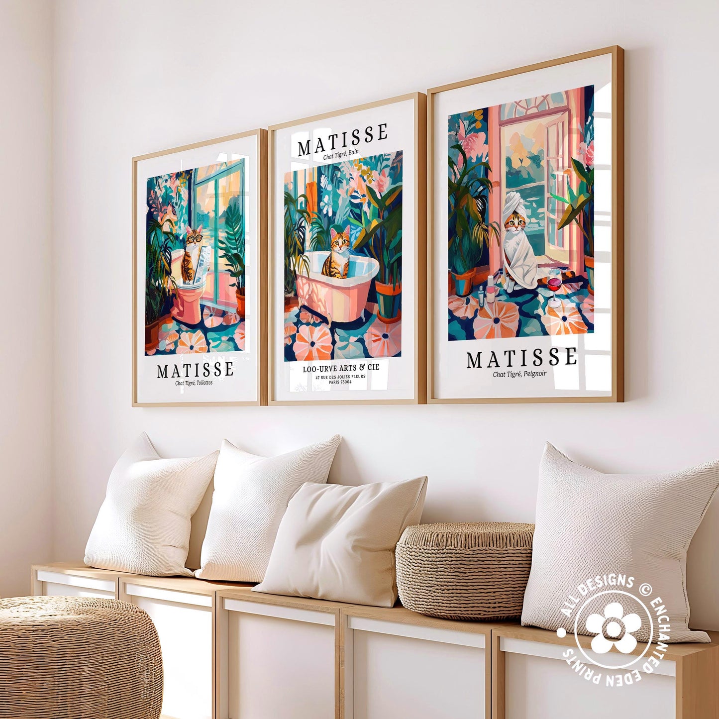three framed prints of the same artwork, each depicting a cat in a different setting, arranged on a wall above a bench with pillows.