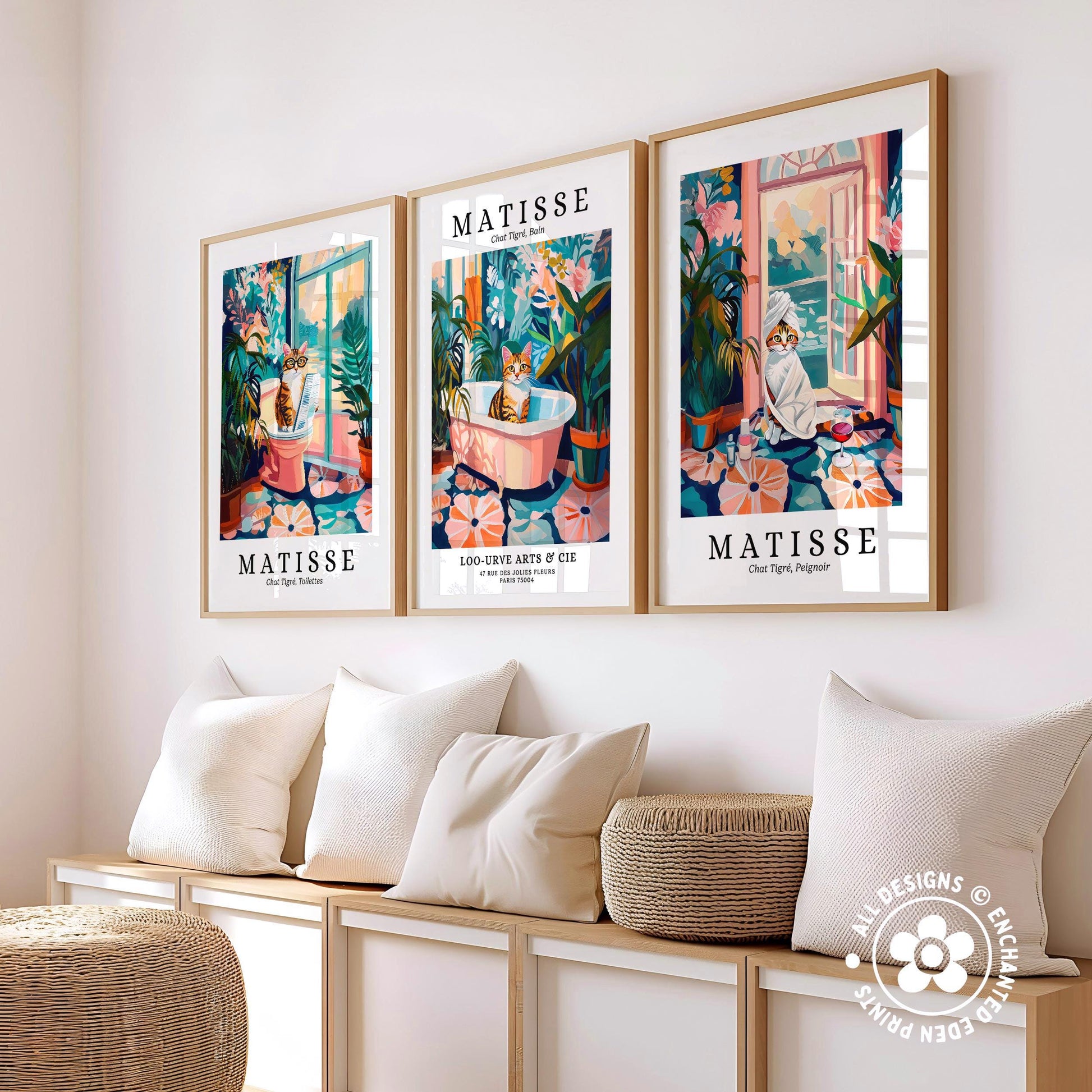 three framed prints of the same artwork, each depicting a cat in a different setting, arranged on a wall above a bench with pillows.
