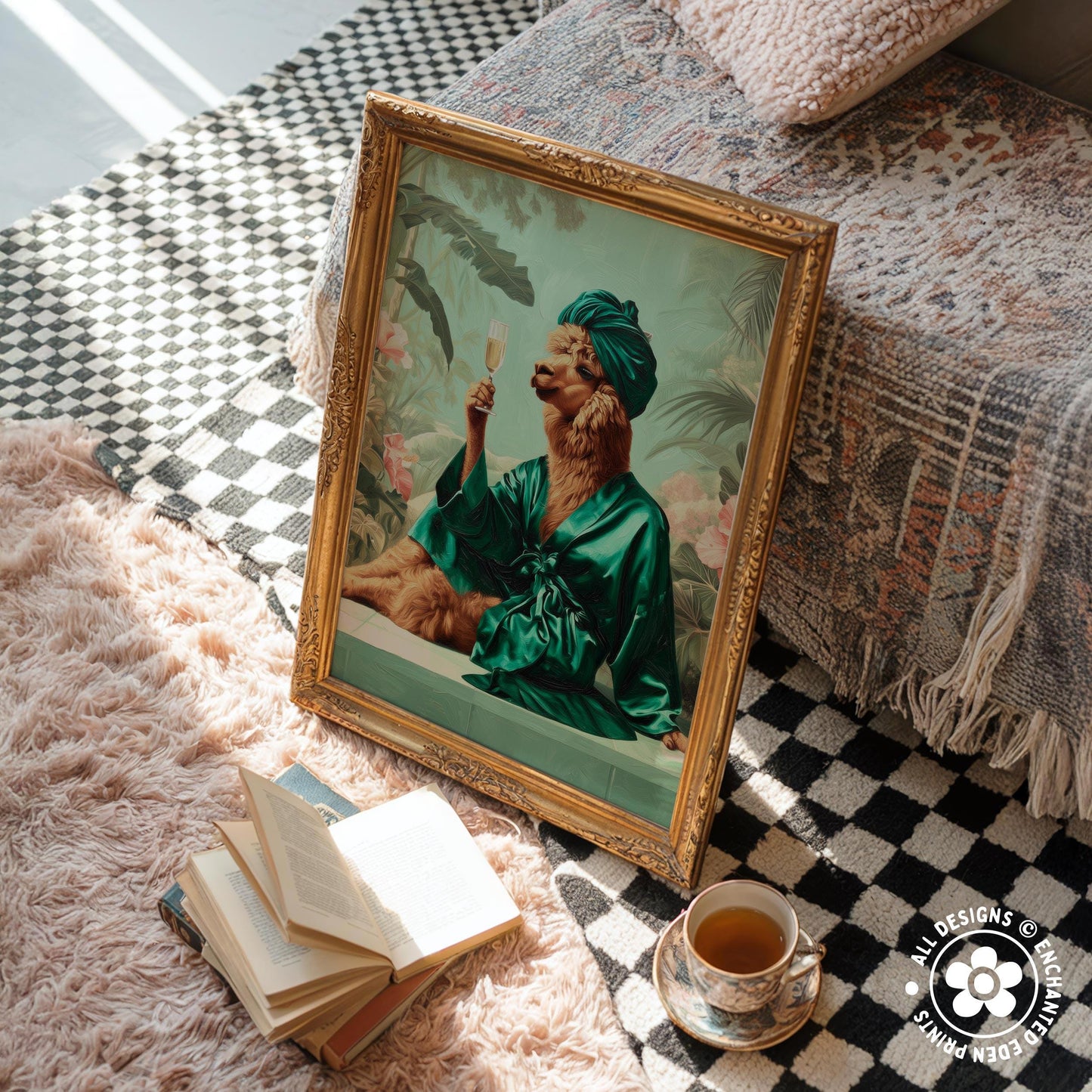 a framed painting of a person in a green robe holding a glass of wine, sitting on a bed with a checkered blanket. Next to the painting, there is a stack of books, a cup of tea, and a small plant.