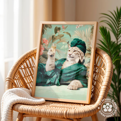 A framed print of a cat wearing a green hat and robe, holding a glass of wine, is displayed on a wicker chair.