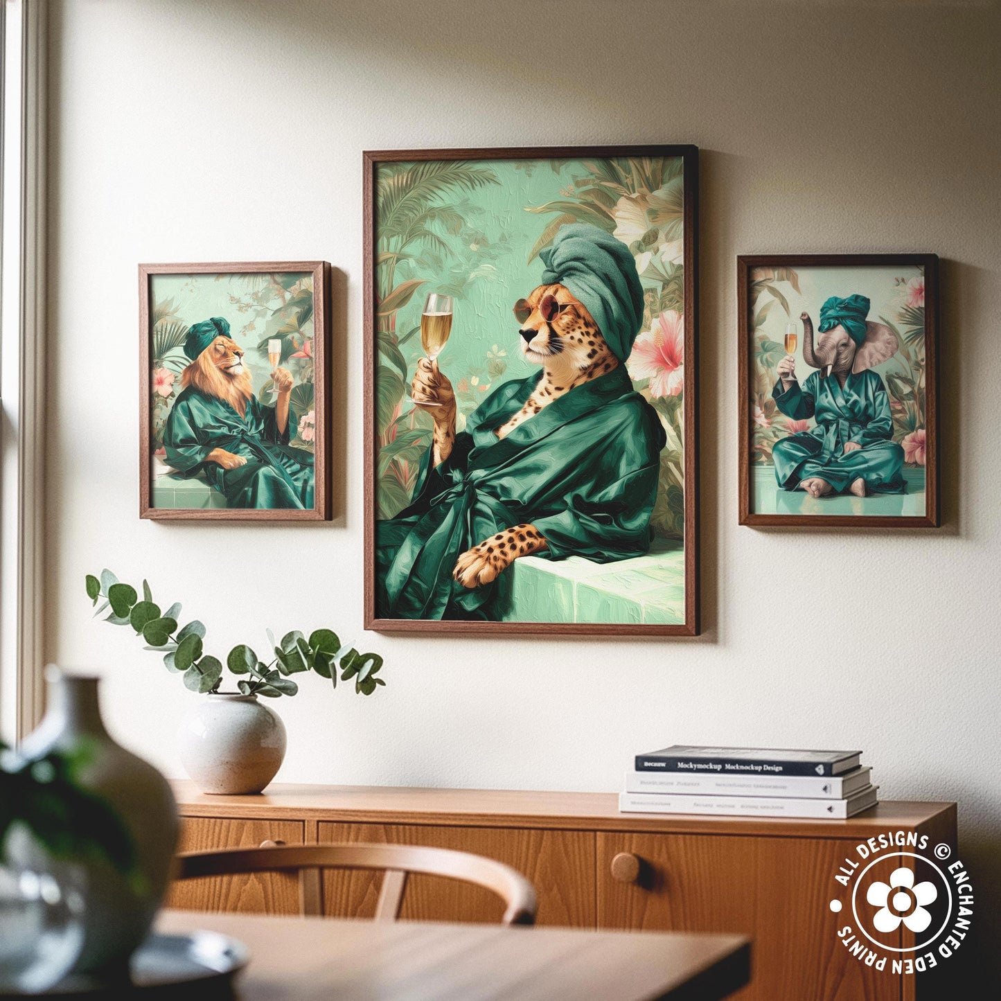a collage of three framed artworks depicting animals in green robes, including a cheetah, a lion, and an elephant, all holding wine glasses. The artworks are displayed on a wall above a wooden cabinet, which also has a vase and some books on it.