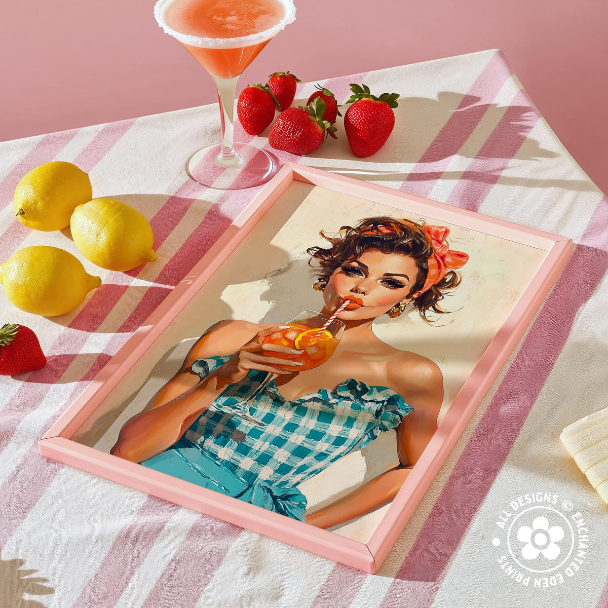 a framed illustration of a woman drinking a cocktail, surrounded by a pink and white striped tablecloth, lemons, strawberries, and a cocktail glass.