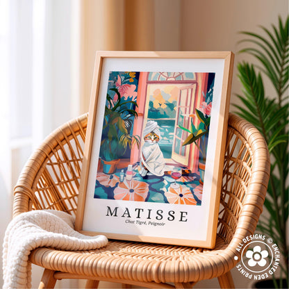 A framed illustration of a cat sitting on a colorful rug, with a tropical garden scene in the background, is displayed on a wicker chair.
