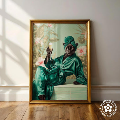 A framed painting depicting a black cat wearing a green robe and holding a glass of wine, sitting on a ledge against a floral background.