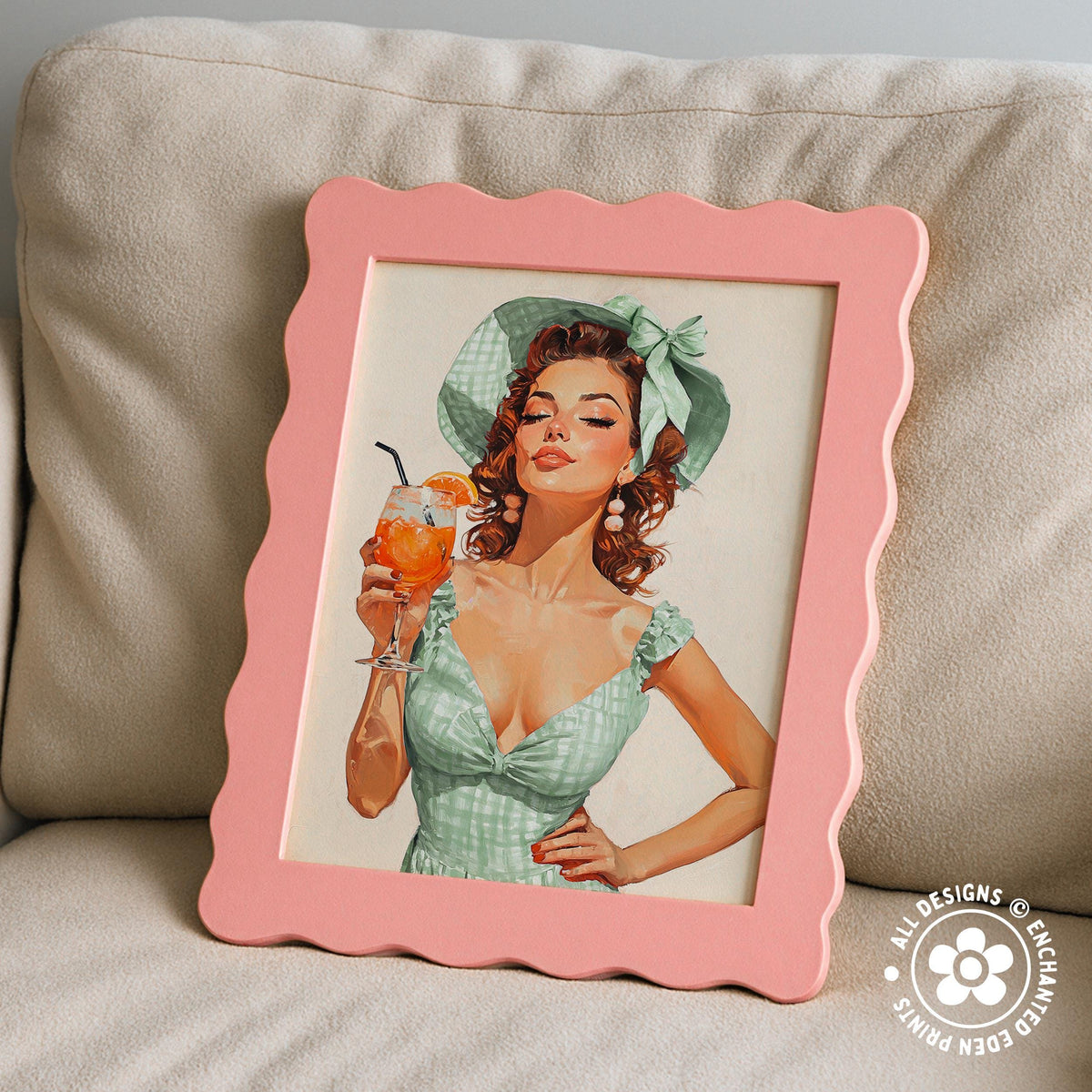 A framed painting of a woman in a green dress holding a glass of orange juice, with a scalloped pink frame.