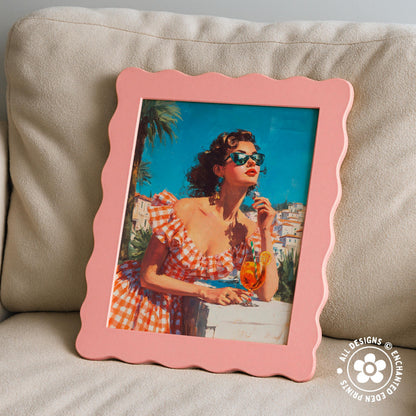 A framed painting of a woman in a red and white checkered dress, wearing sunglasses, holding a drink, and looking out at a cityscape.