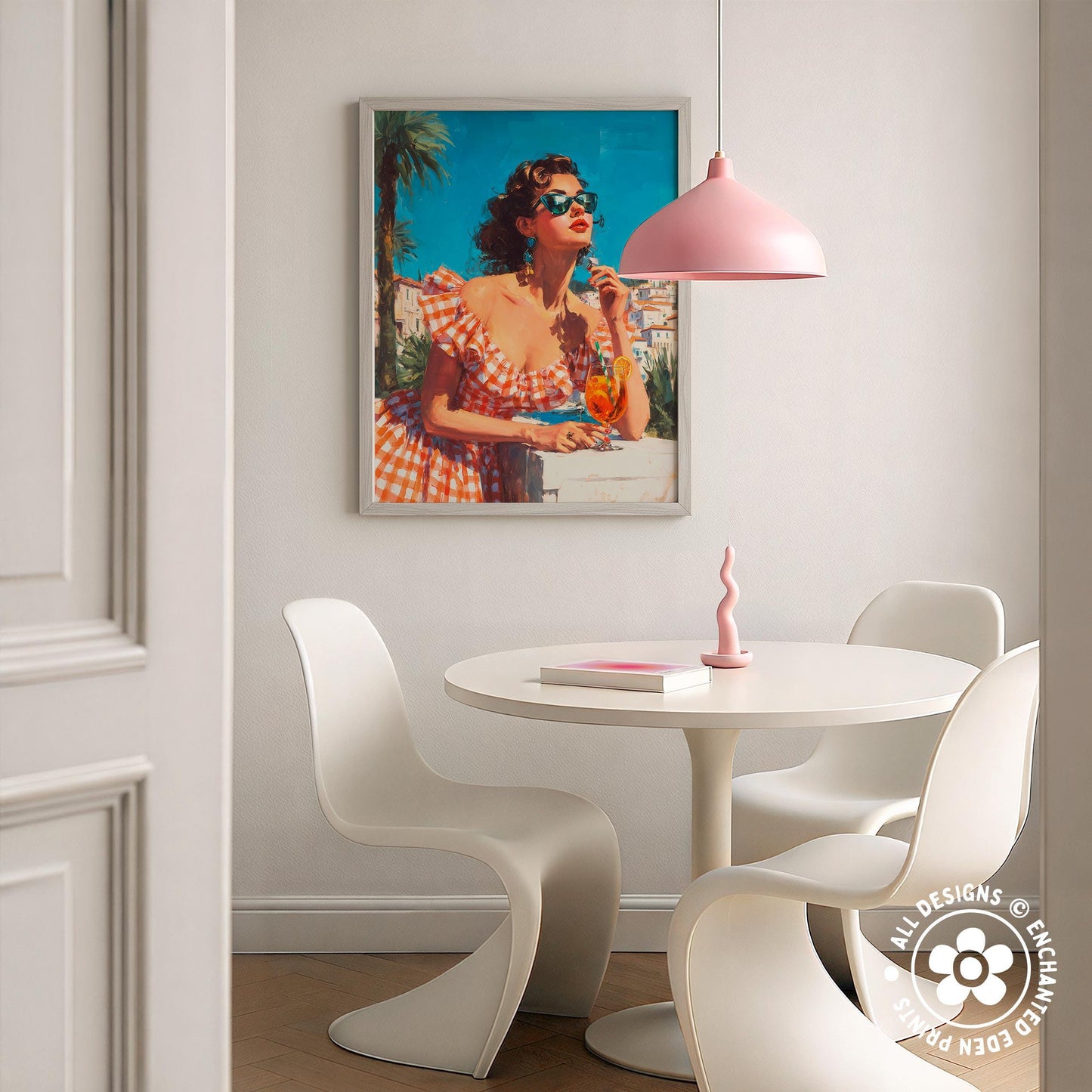 a dining area with a white table and chairs, a framed picture of a woman in a checkered dress, and a pink pendant light hanging above the table.