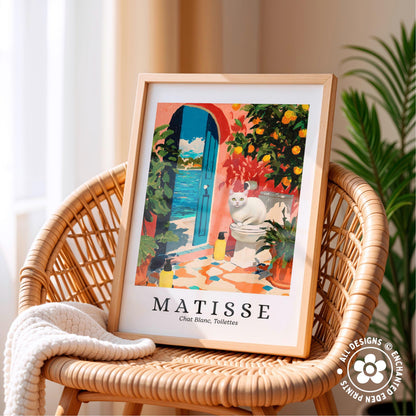A framed print of a colorful painting depicting a cat sitting on a toilet in a tropical setting, with a blue door and orange flowers in the background.