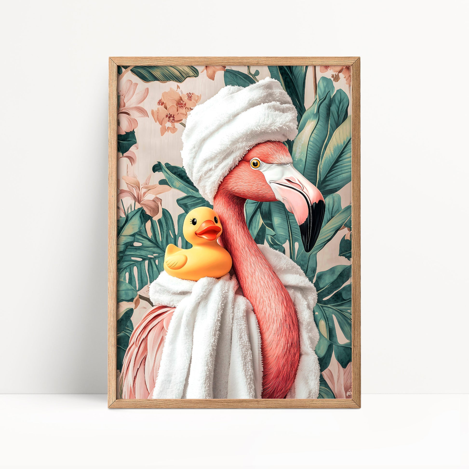 A framed print featuring a pink flamingo wearing a white towel and holding a yellow rubber duck, set against a tropical leafy background.