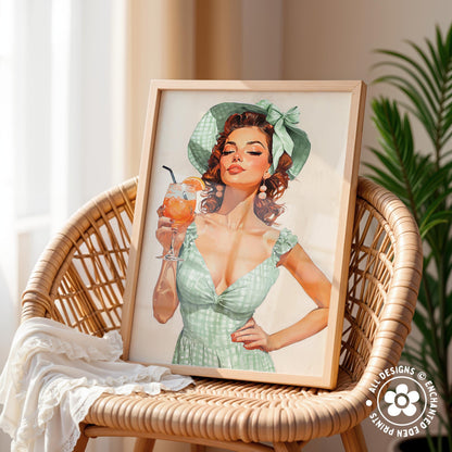 A framed illustration of a woman in a green dress holding a glass of what appears to be a cocktail, with a wicker chair and a plant in the background.