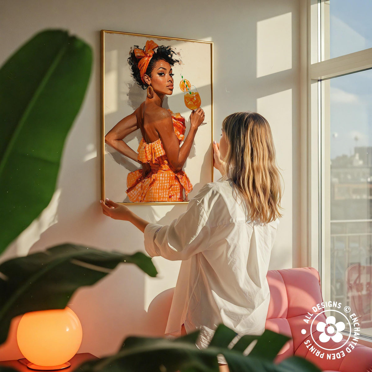 A woman hangs a framed painting of a woman in an orange dress on a wall, with a pink chair and a green plant in the foreground.