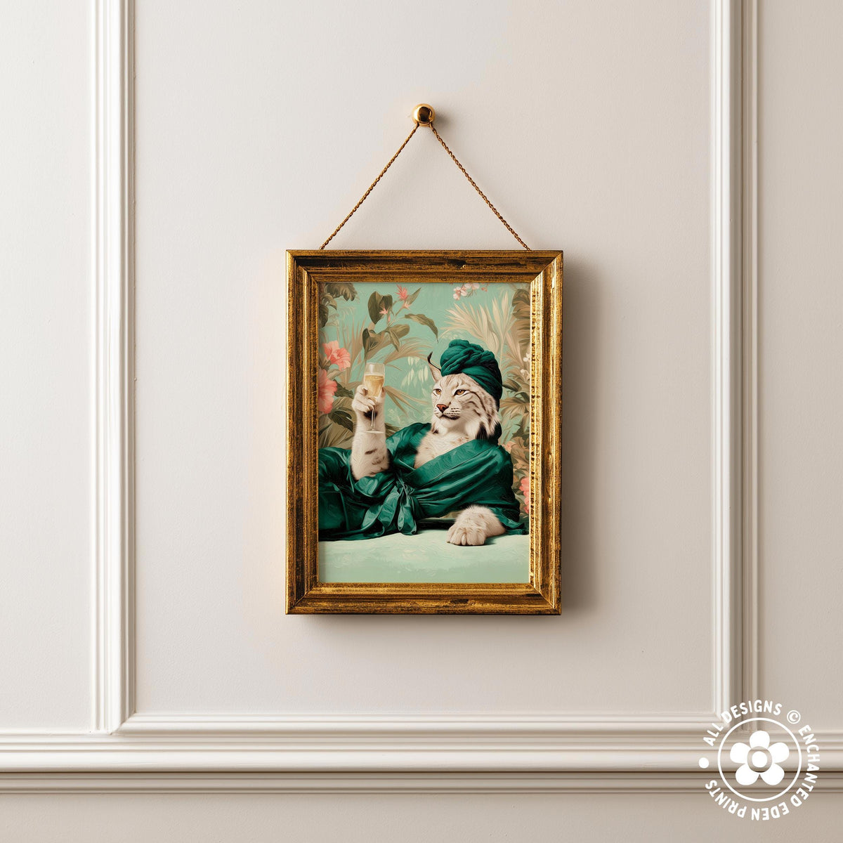 A framed image of a cat wearing a green robe and hat, sitting on a bed and holding a small object in its paw.