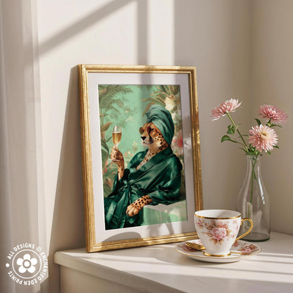 a framed painting of a cheetah wearing a green robe and holding a glass of wine, placed on a white shelf next to a vase of pink flowers and a cup of tea.