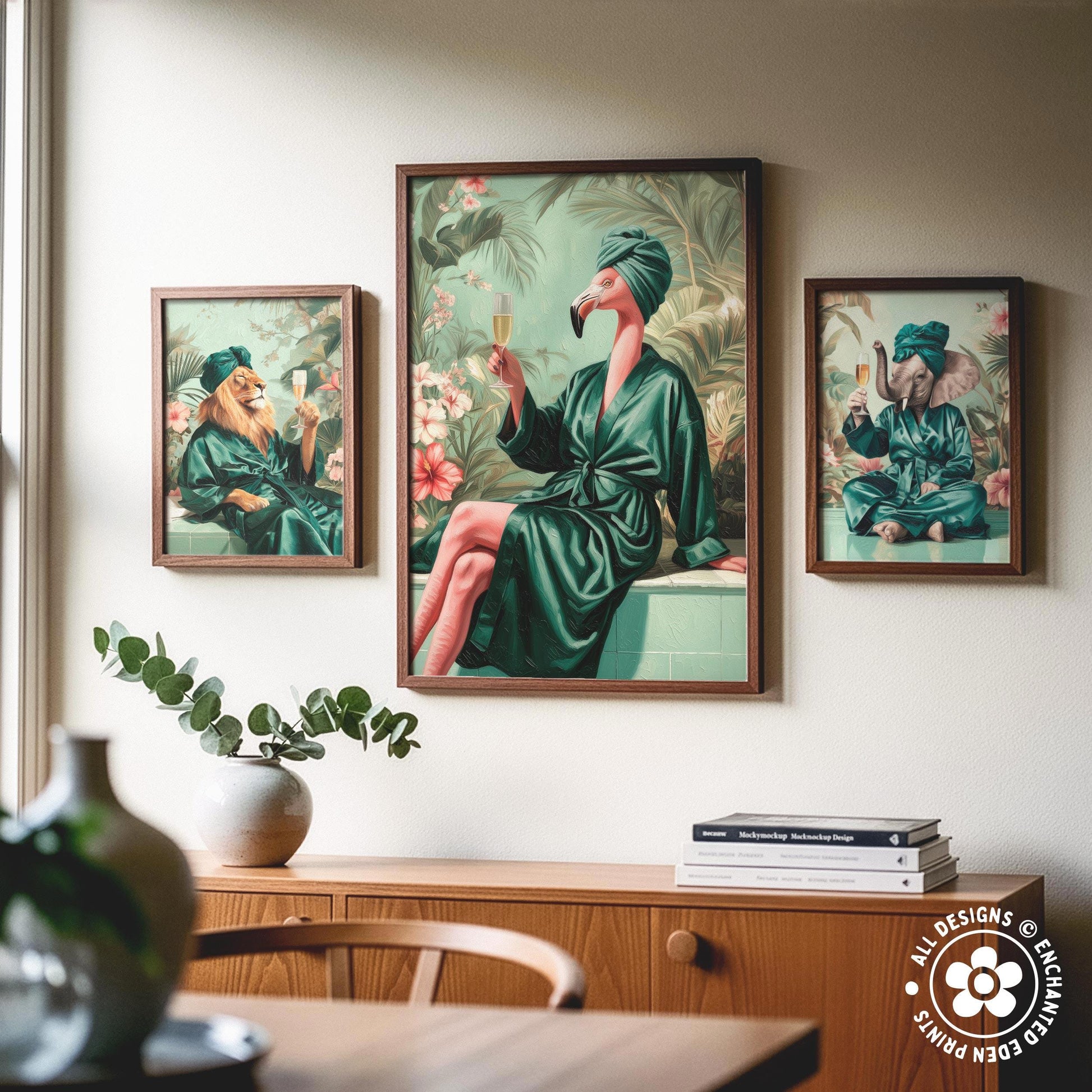 a wooden cabinet with a vase of greenery and a stack of books on top. Above the cabinet, there are three framed paintings depicting a flamingo, a lion, and an elephant in green robes.