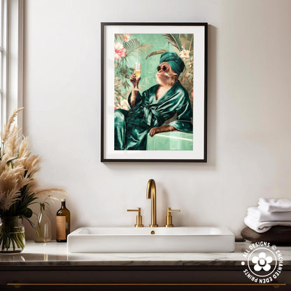 a framed painting of a monkey dressed in a green robe and holding a drink, sitting on a bench in a tropical setting. The painting is hung on a wall above a white sink with a gold faucet.