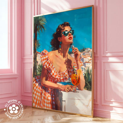 A large framed painting depicting a woman in a red and white checkered dress, wearing sunglasses and holding a drink, standing in front of a pink wall with palm trees and a building in the background.